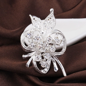 Close-up of silver-plated brooch with pearls and rhinestones in flower bow design