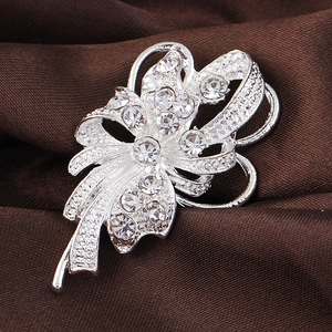 Elegant silver floral brooch with sparkling rhinestones and pearls on dark fabric