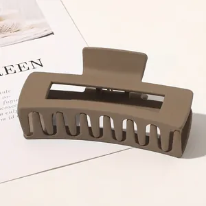 Close-up of a large matte brown rectangular hair claw clip with geometric hollow design