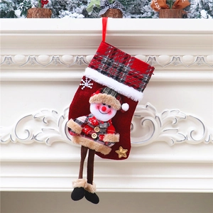 Detail eines roten Weihnachtssöckchens mit langbeinigem Schneemann am Kamin