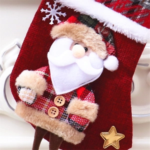 Nahaufnahme eines roten Nikolausstrumpfs aus Stoff mit Plüsch-Weihnachtsmann und Schneeflocken