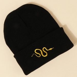 Detail of black knit beanie featuring bright yellow snake embroidery on folded cuff