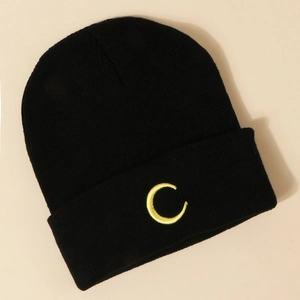 Detailed close-up of a black knit beanie featuring a yellow moon embroidery on the folded cuff
