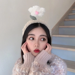 Close-up of model wearing plush cream headband with a soft white flower detail