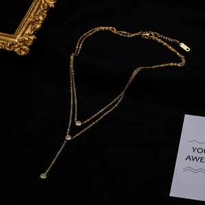 Dettaglio della collana a doppio strato a Y in oro rosa con tre zirconi trasparenti