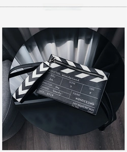 Close-up of film clapperboard design on black PU leather handbag with zipper detail