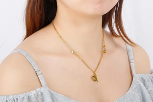 Close-up of a 18K gold plated heart pendant necklace worn by a model on white background