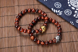 Macro shot of tiger eye bead bracelets with gold and silver skull charms on bamboo mat