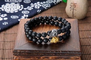 Detail of matte black beaded bracelets with skull accents on a wooden stand
