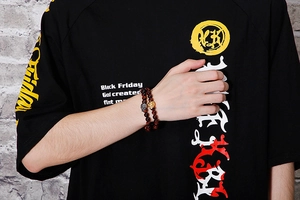 Detail of tiger eye bead bracelet with silver and gold skull charms on wrist