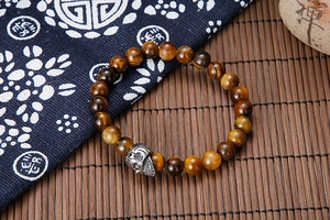 Close-up of natural tiger eye beads and silver skull charm on a beaded bracelet