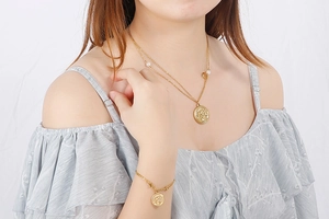 Detail of layered gold coin necklace and pearl bracelet set on a female model