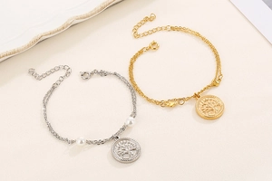 Close-up of gold and silver double-layer bracelets with Tree of Life charms and pearls