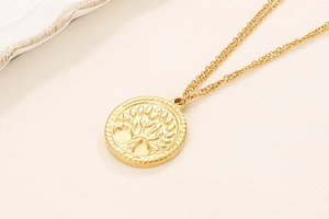 Detail showing gold tree of life circular pendant and double-layer chain on beige fabric
