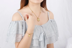 Détail de l'ensemble collier et bracelet dorés en acier titane avec pendentifs ronds