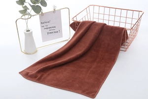 Detailed texture of thick caramel microfiber towel draped on a rose gold metal basket