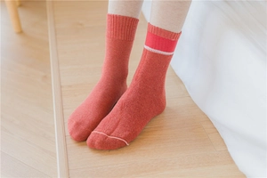 Close-up of warm orange cotton thermal socks with ribbed cuffs on wooden floor