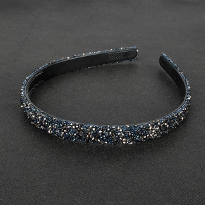 Detail of minimalist headband with black and blue rhinestones on a textured background