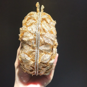 Détail de pochette de soirée dorée avec texture de feuilles 3D et strass brillants