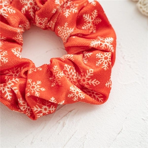 Detailed texture of red velvet Christmas scrunchie featuring white snowflake patterns