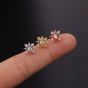 Dettaglio di tre orecchini a vite con stelle in zircone nei colori oro e argento