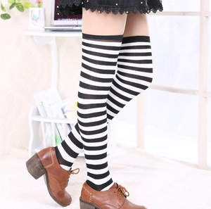 Détail de chaussettes hautes rayées noir et blanc avec jupe en dentelle et souliers
