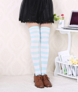 Détail de chaussettes hautes rayées bleu et blanc avec une jupe noire plissée