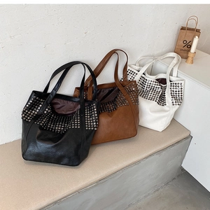 Detailed view of large rivet studded tote bags in black, brown, and white leather