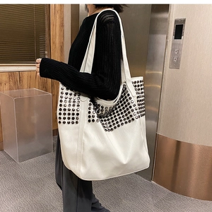 Detail view of large white tote bag with metal rivet accents and premium faux leather texture