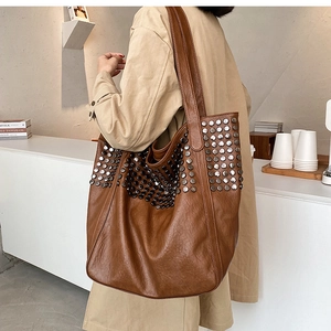 Detailed side view of the brown studded tote bag with vintage leather texture on model