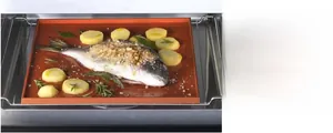 Brown silicone baking mat with raised edges used for roasting fish and potatoes in oven