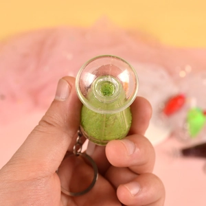 Detailed close-up of a green wine bottle keychain with textured surface and sand filling
