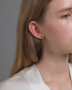 Close-up of elegant gold clip-on earring with a white pearl on a woman's ear