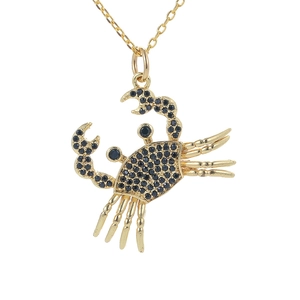 Detailed view of crab pendant with golden alloy setting and black crystal inlay