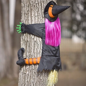 Detail of colorful crashing witch decoration with purple hair on a tree for Halloween