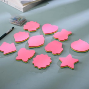 Flat lay of colorful multi-shaped sticky notes including hearts and stars on blue surface