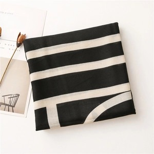 Detailed flat lay of breathable black and white striped scarf with aesthetic dry flower