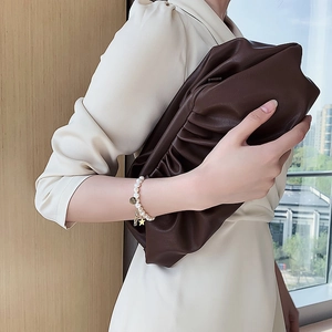 Brown pleated clutch bag paired with baroque pearl bracelet and gold star charms
