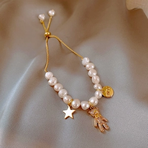 Macro view of adjustable pearl bracelet with gold micro-pave bear and heart charms