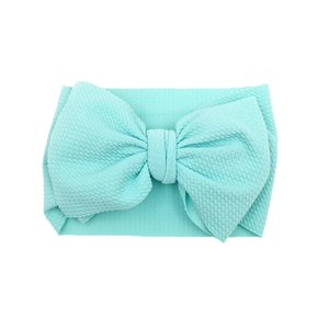 Close-up of mint green waffle fabric texture on a wide baby headband with a large bow