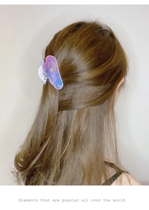 Rear view of model wearing a purple cloud-shaped hair claw with moon and star patterns