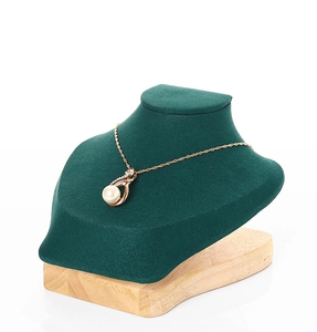 Detail of white pearl necklace on green velvet bust with natural wooden base stand