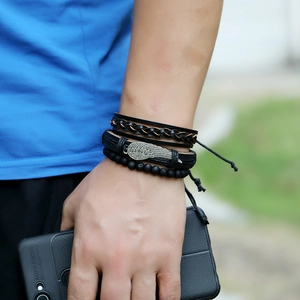 Close-up of multilayer leather bracelet set with wing charm on a model's wrist