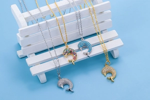 Macro shot of dolphin fishtail pendants with colorful zircons on a white mini bench