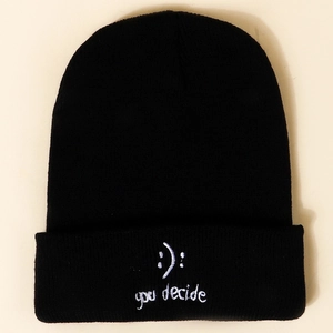 Close-up of black knitted beanie featuring white smile face and you decide embroidery