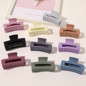Detailed view of ten matte hair claws in various elegant colors arranged on a beige surface