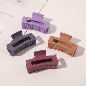 Detail of four matte rectangle hair claws in purple, grey, tan and burgundy colors