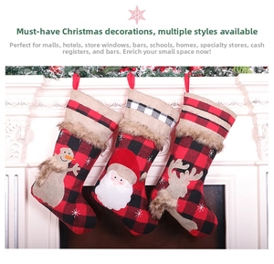 Three plaid Christmas stockings with Santa, snowman and reindeer hanging on a white fireplace