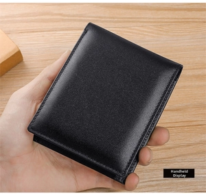 Close-up of black pebble grain leather men's trifold wallet held in hand for size display