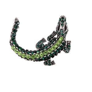Exaggerated silver crocodile brooch with sparkling green crystals and black gemstone eye